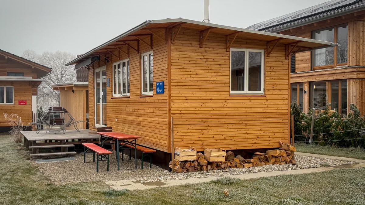 A charming wooden cabin with a small porch in a peaceful countryside location.